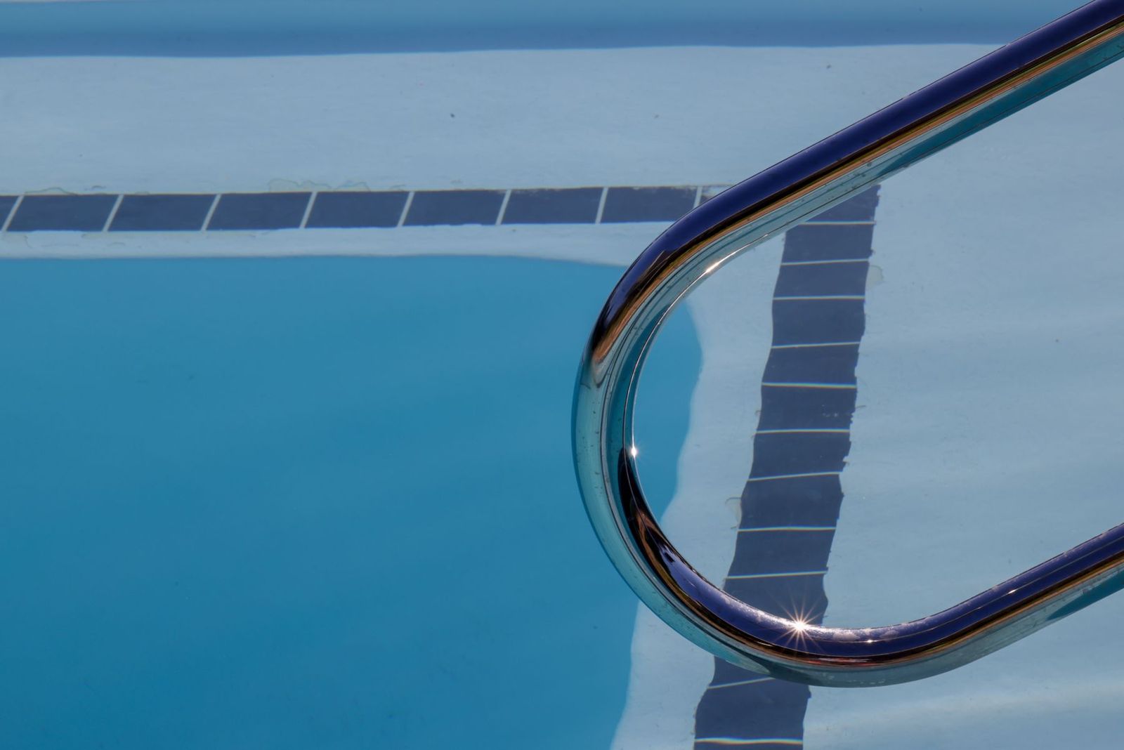 Schwimmbecken mit Leiter, Sonnenreflexe auf dem Wasser